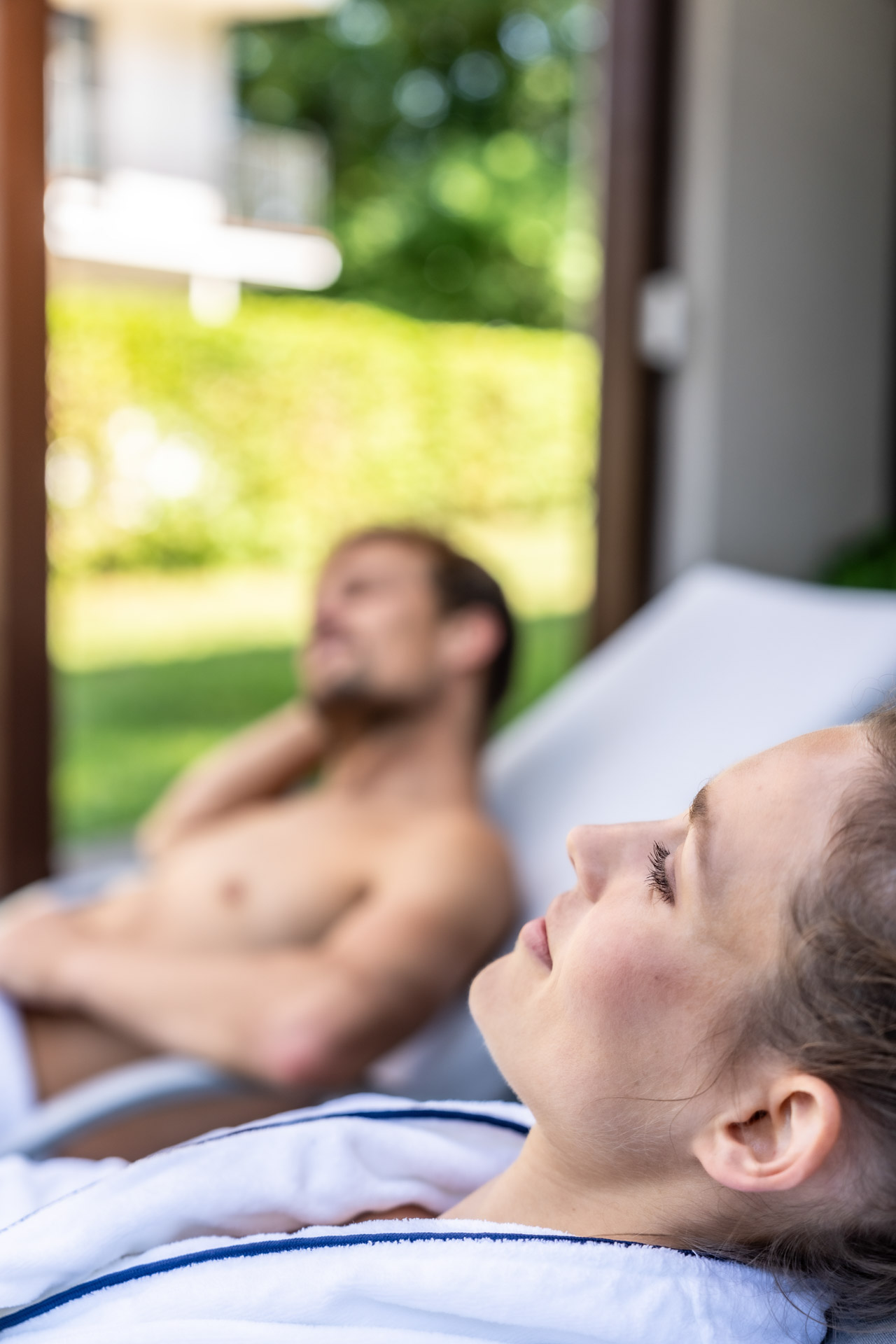 Mann und Frau, welche sich auf Liegen der Terrasse der Apartments entspannt